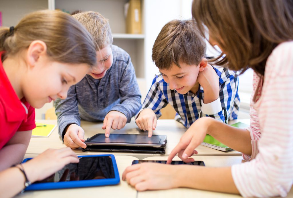 education, elementary school, learning, technology and people concept - group of school kids with tablet pc computer having fun on break in classroom